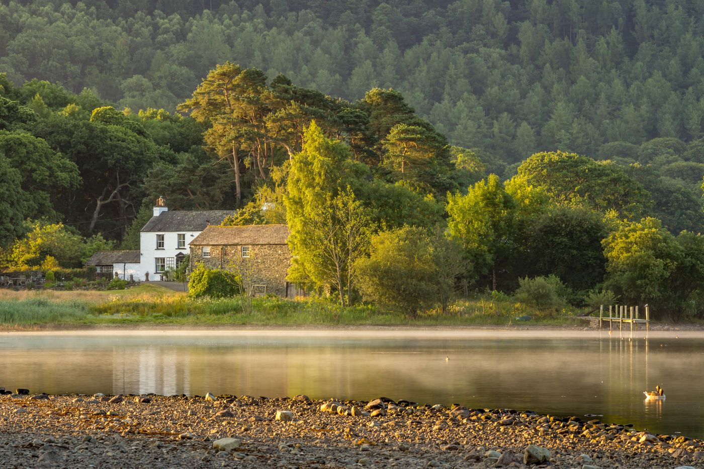 A white stone cottage beside a still lake in Cumbria