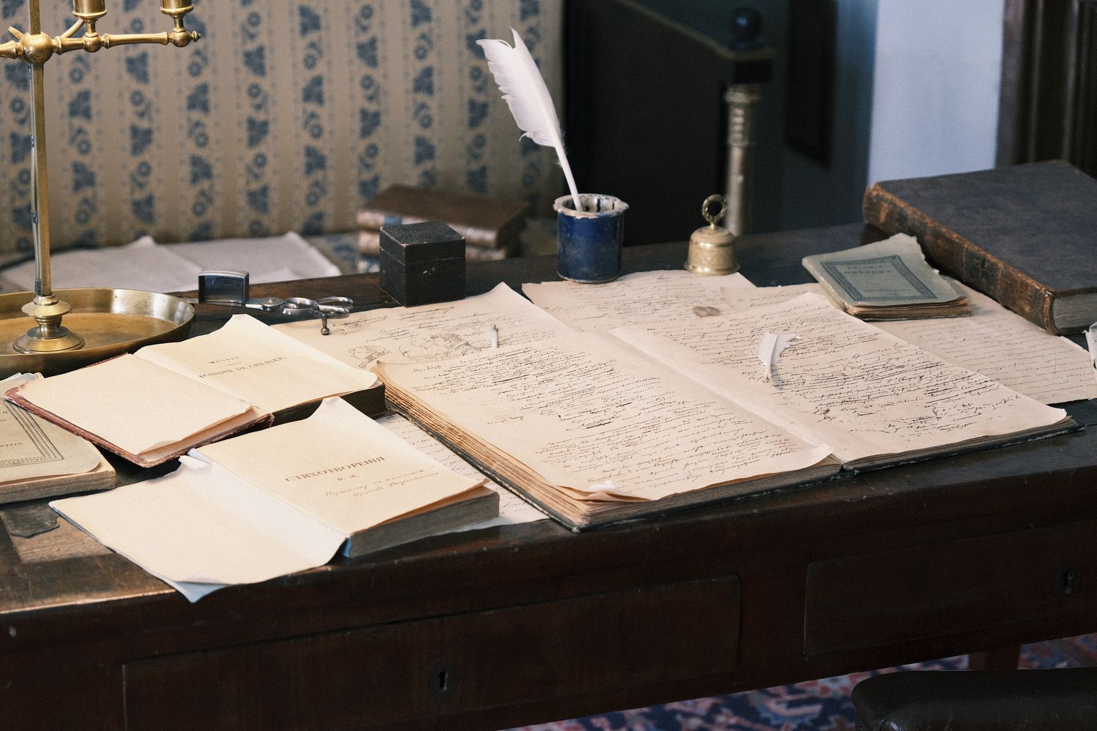 An open ledger of handwritten entries beside correspondence and bound volumes