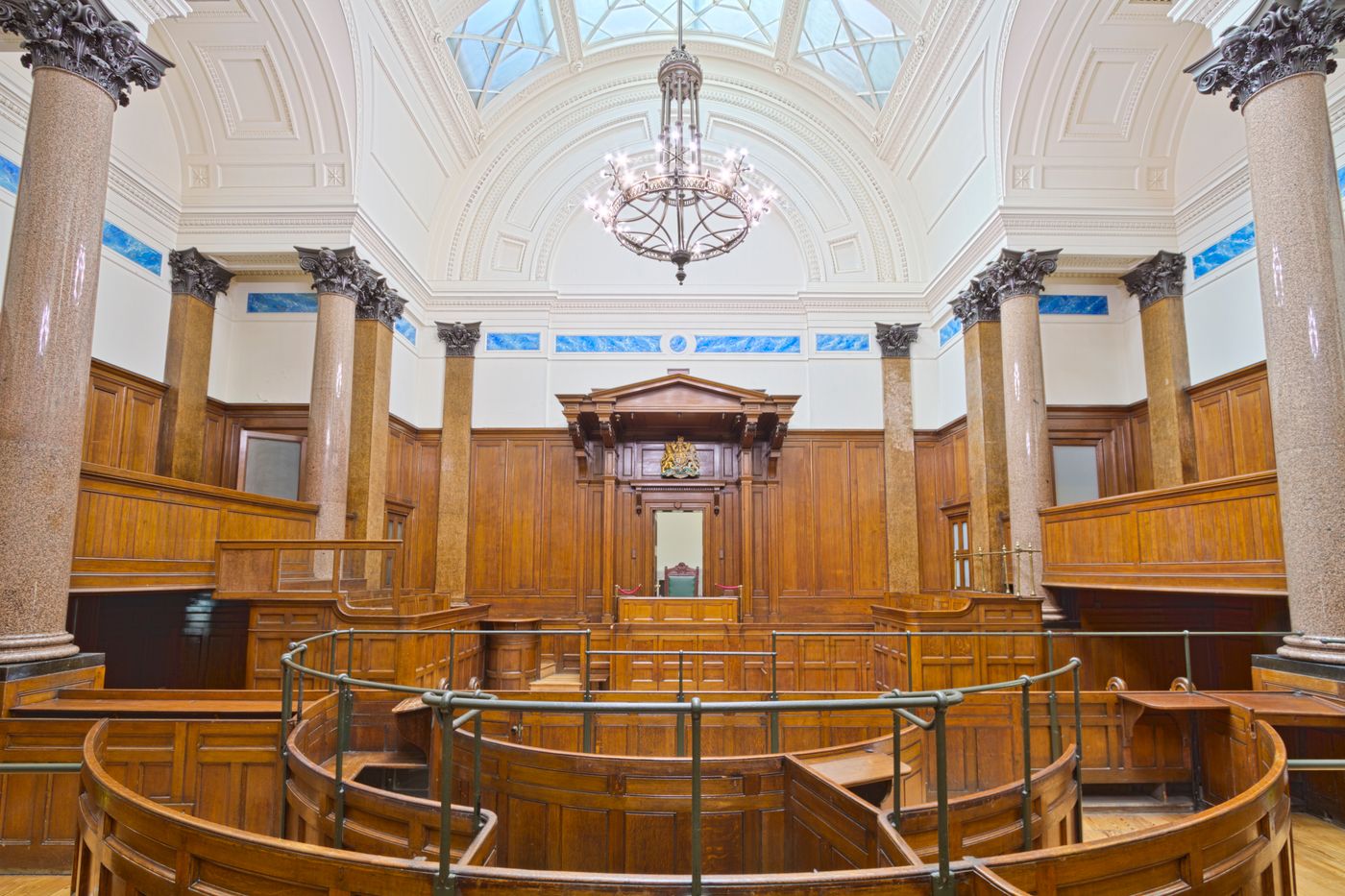 A paneled room with stone columns beneath a glazed roof light
